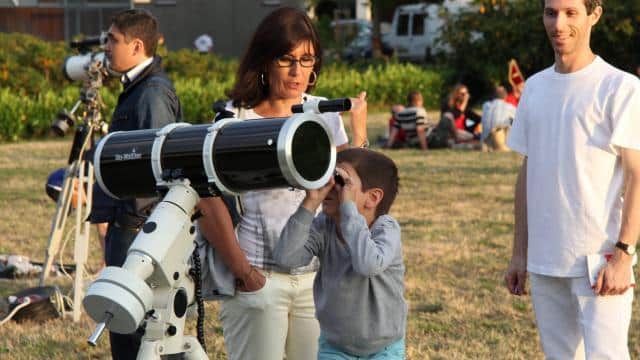 un enfant avec sa mère visualisant les étoiles avec le telescope