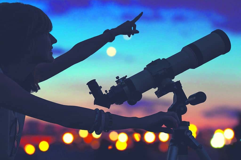 une fille observant les étoiles à travers un télescope